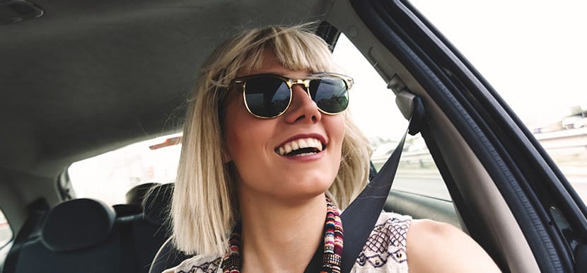 A young woman wearing sunglasses sitting in a car.