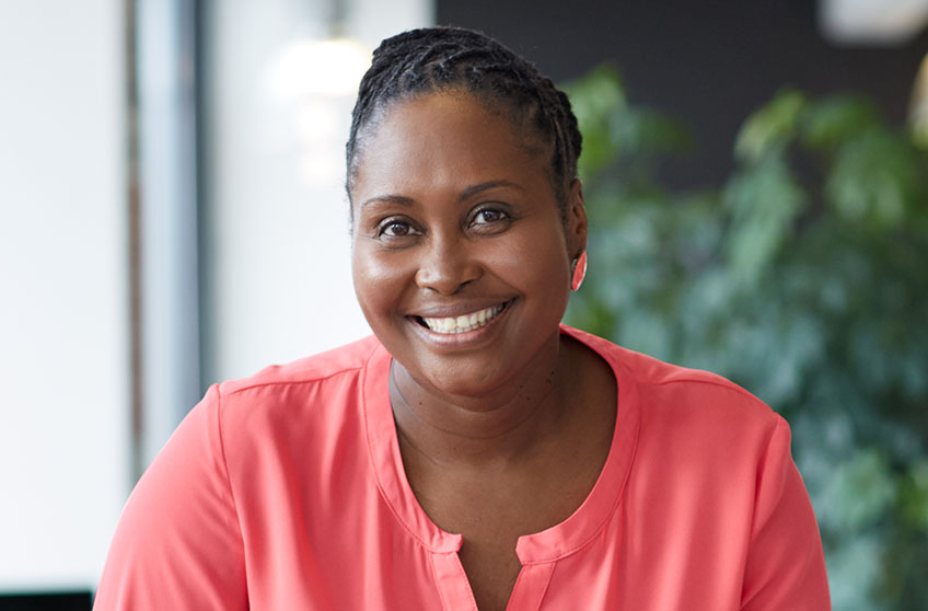 Headshot of future staff member, a woman wearing a pink shirt in an office.